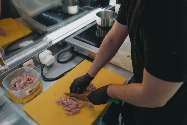 Découpe de viande crue sur une planche de cuisine, geste associé au risque d'intoxication alimentaire