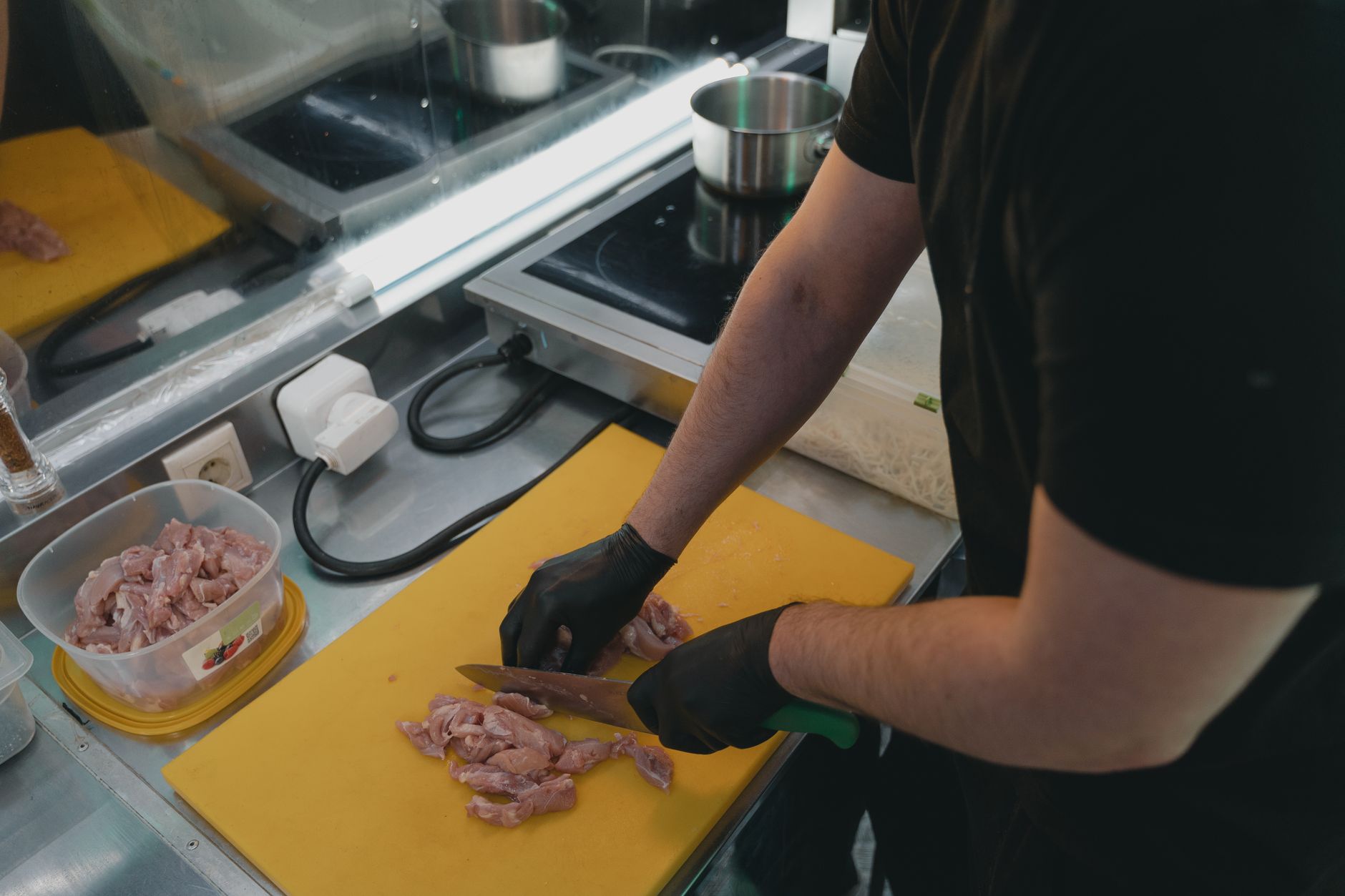 Découpe de viande crue sur une planche de cuisine, geste associé au risque d'intoxication alimentaire