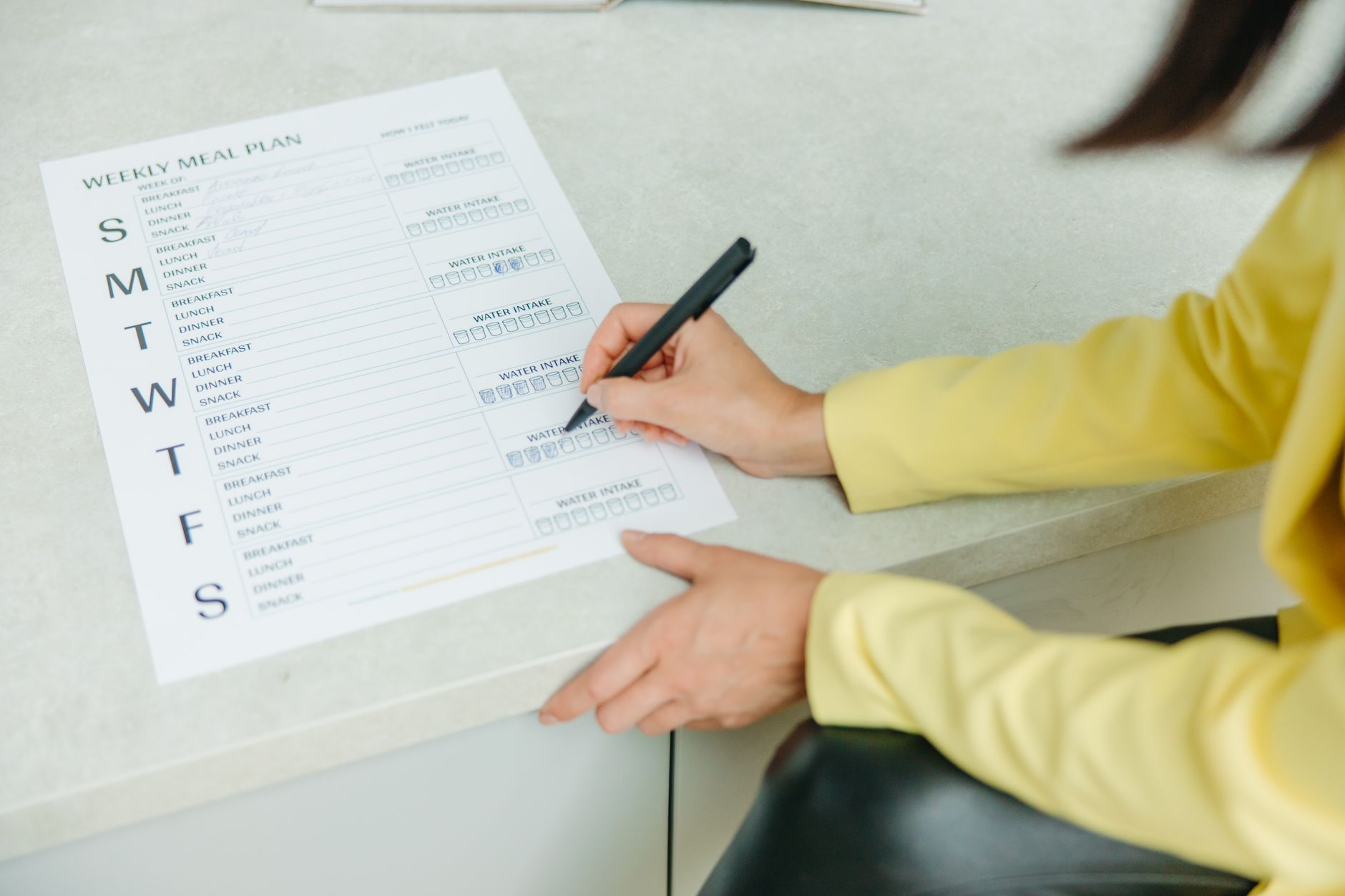Personne remplissant à la main un menu de semaine équilibré dans un carnet